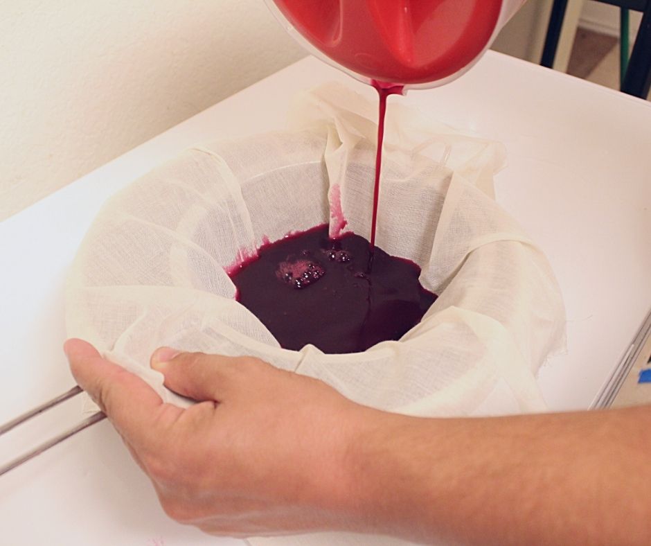 straining the mustang grape juice through cheesecloth