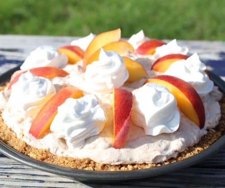 Whipped peach pie with sliced peaches and whipped cream on top in the sun