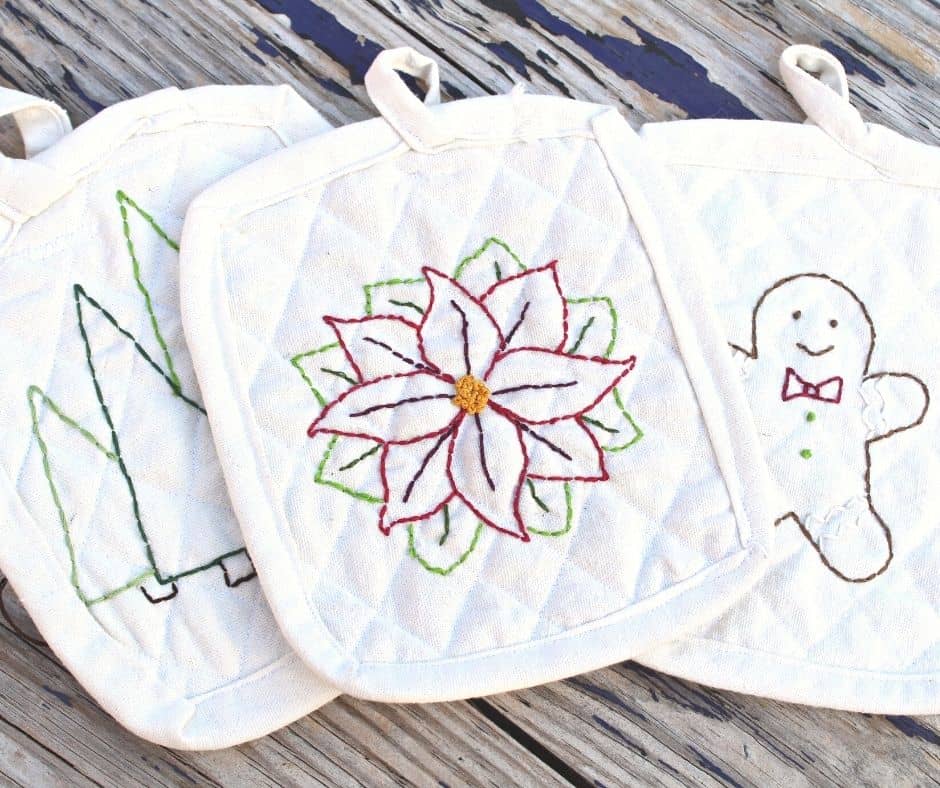 three bleached drop cloth potholders with Christmas embroidery on the tops