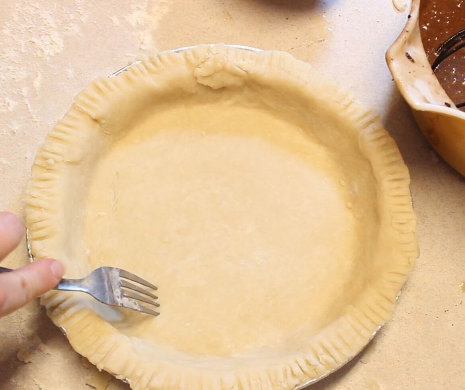 easy pie crust in a pie pan being poked with a fork