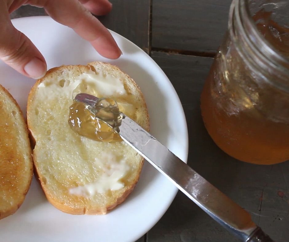 honey mesquite bean jelly being spread onto buttered toast