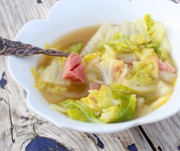 cabbage soup with ham in a white bowl
