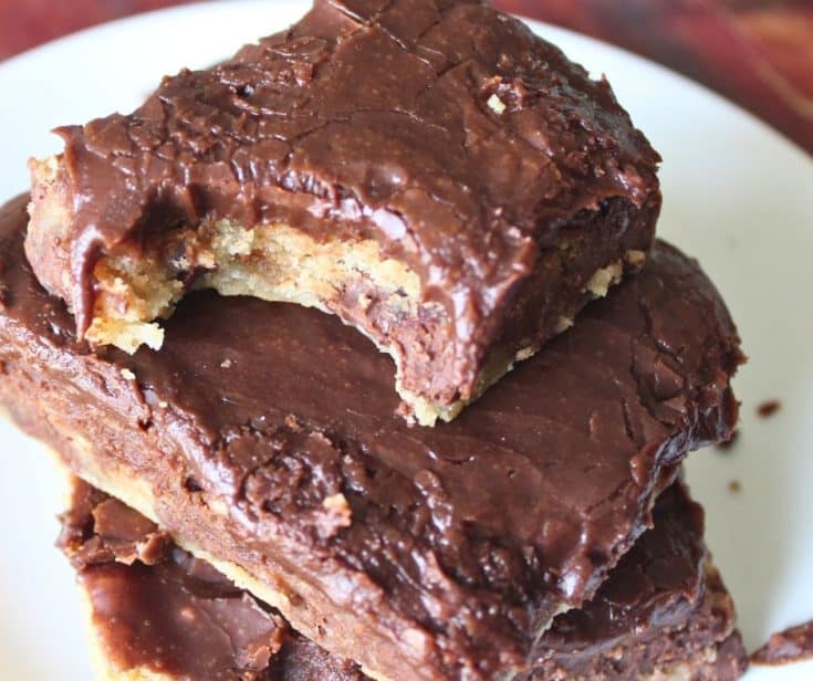 chocolate chip cookie bars with chocolate frosting stacked on a white plate