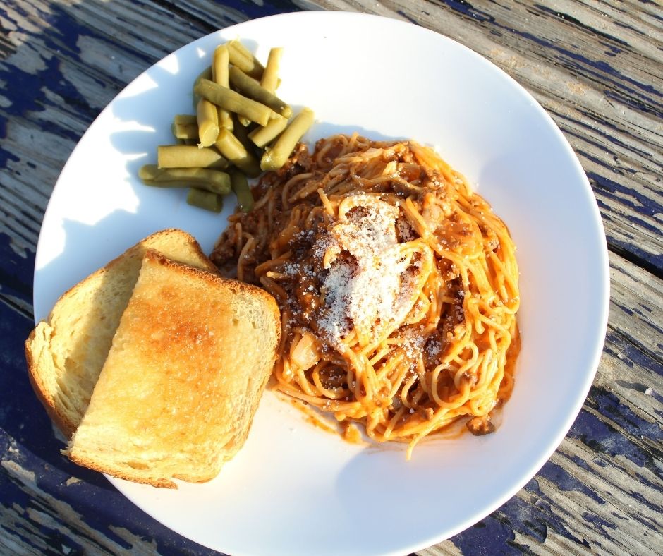 creamy spaghetti with garlic bread and green beans on a plate